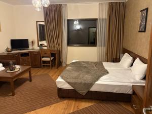 a hotel room with a bed and a table and a desk at Hotel Smilen in Smolyan