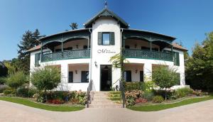 a white building with a balcony on top of it at Villa Millennium in Balatonalmádi