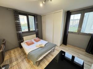 a small bedroom with a bed and two windows at Studio fonctionnel Beauvais in Beauvais