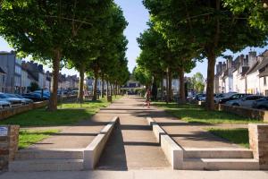 a street with trees and a person walking down a sidewalk at Studio cosy in Saint-Yrieix-la-Perche