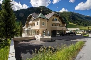 ein großes Haus mit einem Berg im Hintergrund in der Unterkunft Hotel Neder in Ischgl