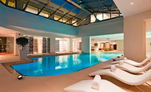 a swimming pool with white chairs in a building at Porto Platanias Beach Resort & Spa in Plataniás