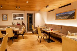 ein Restaurant mit Holzdecken, Tischen und Stühlen in der Unterkunft Hotel Neder in Ischgl