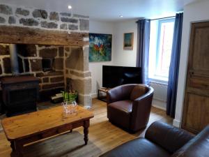 a living room with a stone fireplace and a leather chair at Maison Village Hautefage avec piscine chauffée in Hautefage