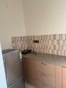 a kitchen with a stainless steel refrigerator and tiles on the wall at The elf stays in Dehradun