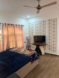 a bedroom with a bed and a television and a desk at The elf stays in Dehradun