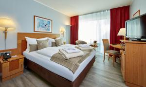 ガルミッシュ・パルテンキルヒェンにあるHotel Königshofのベッドとテレビが備わるホテルルームです。