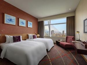 two beds in a hotel room with a large window at Grand Mercure Danang - 10 minutes to Airport & 200m to Bach Dang Walking street in Danang +137 photos