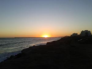 una puesta de sol sobre el océano con la puesta de sol en Casa Vacacional Los Nietos en Quequén