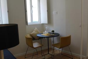 een kleine tafel in een kamer met stoelen en een raam bij Casa da Maria Alfama in Lissabon