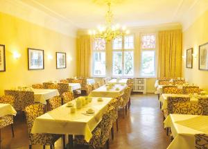a dining room with tables and chairs and a chandelier at Kurfürst am Kurfürstendamm in Berlin