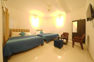 a bedroom with two beds and a chair and a mirror at Cozy retreat in Mysore