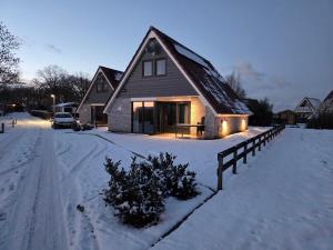 a house is covered in snow with a fence at De Wieringerheid 162 in Den Oever