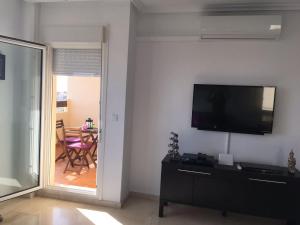 Una sala de estar con un televisor y una mesa con sillas. en Jumilla III, en Orihuela Costa