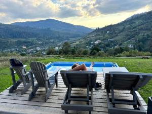 a person laying on a deck next to a swimming pool at Trostjn house in Slavske