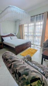 a bedroom with a large bed and a large window at NL Josephine's Apartment in Kampala