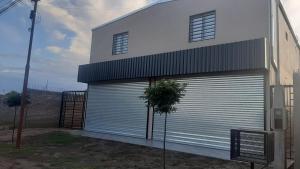 a white building with a large metal garage door at El Rincon del Descanso in General Alvear