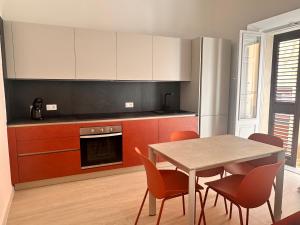 a kitchen with a table and chairs and a refrigerator at Vico Rosso - Milù Holidays La Maddalena in La Maddalena