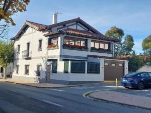 a white house with a car parked in front of it at El Rincón de San Fermín in Zizur Mayor