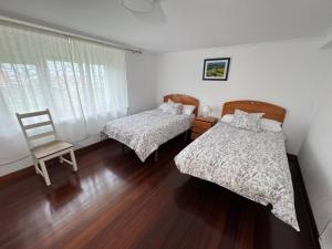 a bedroom with two beds and a chair at La casa del Rubio in Pedreña
