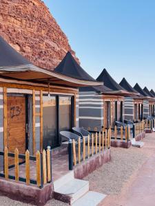 a row of lodges with black roofs at DESERT HELO lUXURY CAMP & TOUR in Wadi Rum