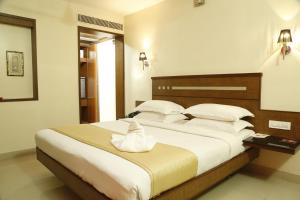 a bedroom with a large bed with white sheets and pillows at HOTEL GRAND PLAZzA in Coimbatore