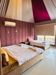 two beds in a room with red and purple walls at DESERT HELO lUXURY CAMP & TOUR in Wadi Rum +44 photos