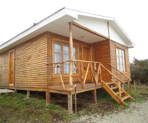 a log cabin with a porch and a staircase at Cabañas Campestres Las Rosas in Punta Arenas