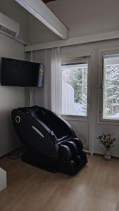 a black couch in a room with two windows at Rivitalo kylpylän lähellä in Kilvakkala