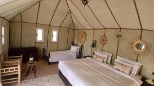 a bedroom with two beds in a tent at Sunshine luxury desert camp in Merzouga