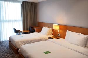 a hotel room with two beds and a window at Hotel Tour Incheon Airport Hotel & Suites in Incheon