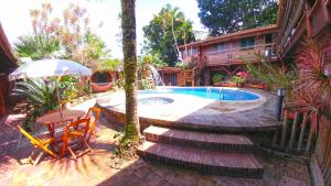 um quintal com uma piscina, uma mesa e cadeiras em Pousada Enseada dos Búzios em Ubatuba