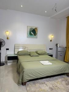 a bedroom with a large green bed with two lamps at Precious Pavilion - Single Rooms in Abuja