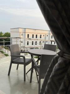 a table and chairs on a balcony with a building at Precious Pavilion - Single Rooms in Abuja
