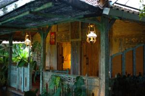 a wooden house with a porch with a chandelier at Nauna Villa Bali in Ubud