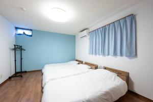 two beds in a room with a window at お宿 春Haru in Muromoto