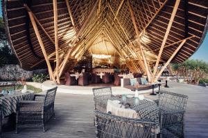 a restaurant with tables and chairs and a large roof at Suarga Padang Padang in Uluwatu