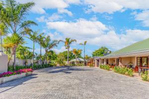 a road in front of a building with palm trees at Caledon 23 Guest House in George