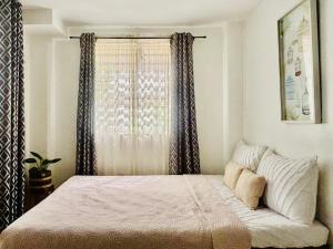 a bedroom with a large bed with a window at Balai Lawaan Cozy Homestay in Iloilo City