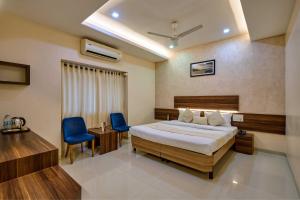 a bedroom with a bed and two blue chairs at Hotel Rajpurush in Kolhapur