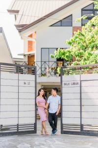 a man and a woman standing in front of a building at Balai Lawaan Cozy Homestay in Iloilo City