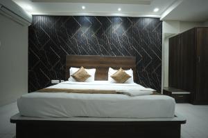 a bedroom with a large bed with a wooden headboard at Hotel Jay Palace in Kota