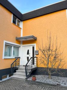 a orange building with a white door and stairs at Ferienwohnung Fatlume No 3 in Bad Honnef am Rhein