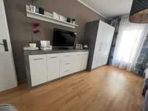 a living room with a tv and white cabinets at Monteurzimmer Grüner Winkel in Lembruch