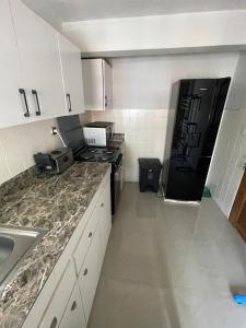 a kitchen with white cabinets and a black refrigerator at Downtown Gombe Haut-Commandement in Kinshasa