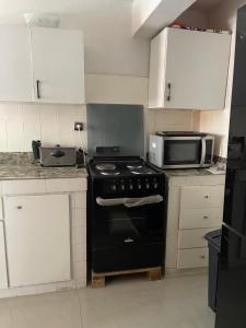 a kitchen with a black stove and a microwave at Downtown Gombe Haut-Commandement in Kinshasa