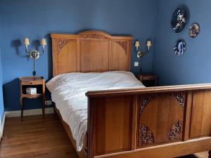a bedroom with a wooden bed and blue walls at Veï Lou Quéri in Moutier-Malcard