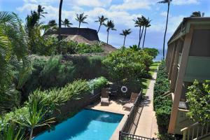 a swimming pool next to a building with palm trees at Kihei Kai Oceanfront Condos in Kihei