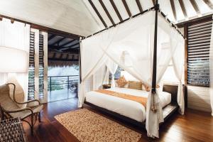 a bedroom with a bed with a canopy at Suarga Padang Padang in Uluwatu