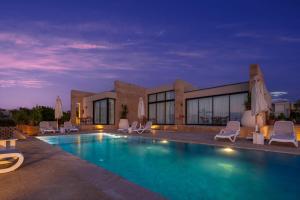 a swimming pool with chairs and a building at Med IL Caesar ADULT ONLY in Zāwiyat al ‘Awwāmah